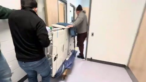 two movers guiding a hospital bed through a doorway