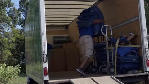 mover loading moving blankets and hand trucks inside a box truck