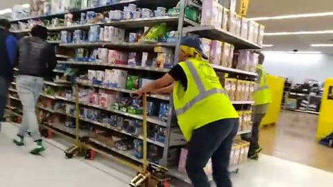 crew pushing a loaded grocery gondola shelving unit on skates